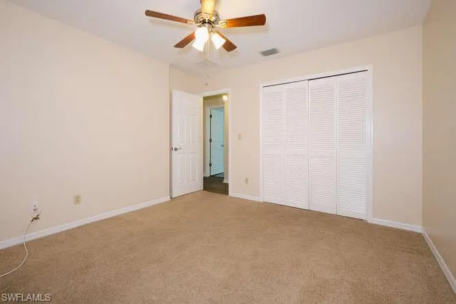Unfurnished bedroom featuring light carpet, ceiling fan, and a closet