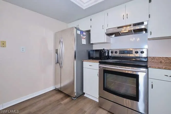 Kitchen featuring dark wood-type flooring, white cabinets, and stainless steel appliances