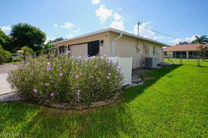 View of property exterior with a yard, a garage, and central air condition unit