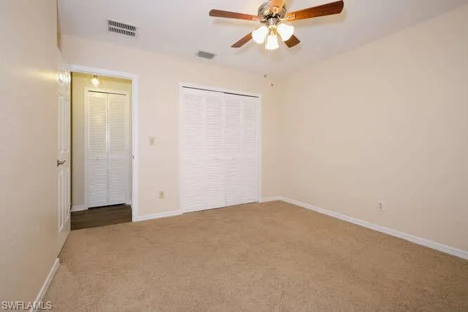 Unfurnished bedroom featuring a closet, ceiling fan, and light carpet