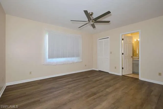 Unfurnished bedroom with a closet, ceiling fan, connected bathroom, and dark hardwood / wood-style flooring
