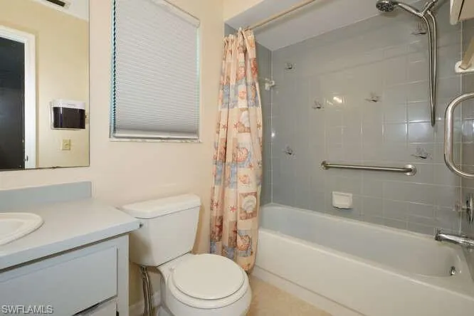 Full bathroom with shower / bath combo with shower curtain, toilet, and vanity