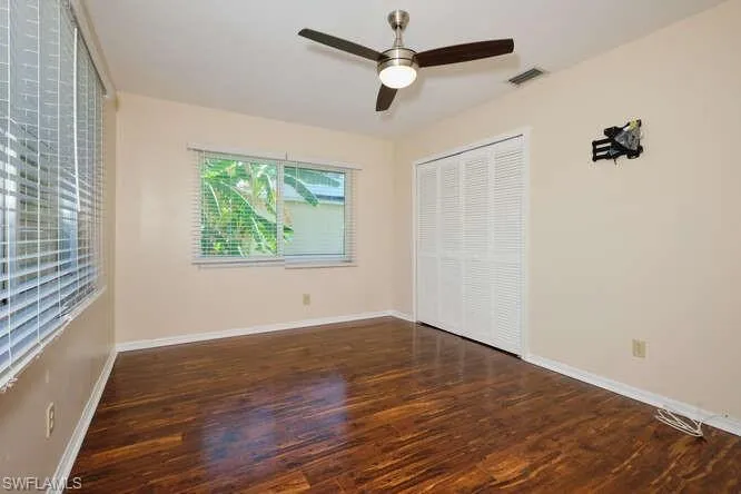 Unfurnished bedroom featuring ceiling fan, a closet, and dark hardwood / wood-style flooring