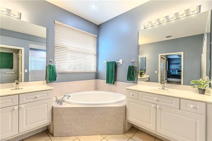 Bathroom featuring separate vanities, and relaxing bathtub