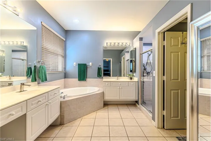 Bathroom with tile flooring, shower with separate bathtub, 2 vanities