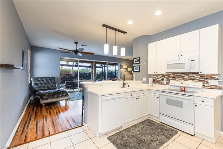 Kitchen with breakfast bar, white cabinetry, light tile floors
