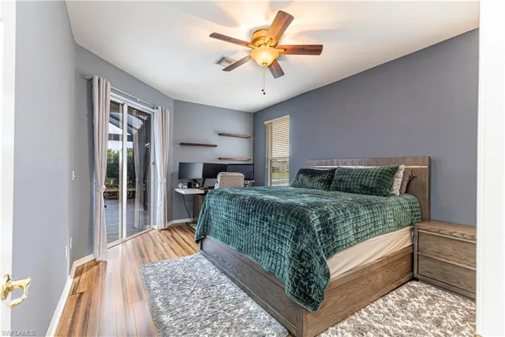 Spacious Bedroom with ceiling fan, wood floors, and access to pool/lanai