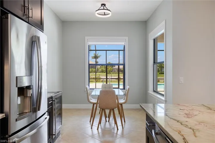 Kitchen with stainless steel fridge, healthy amount of natural light, light stone countertops, and baseboards