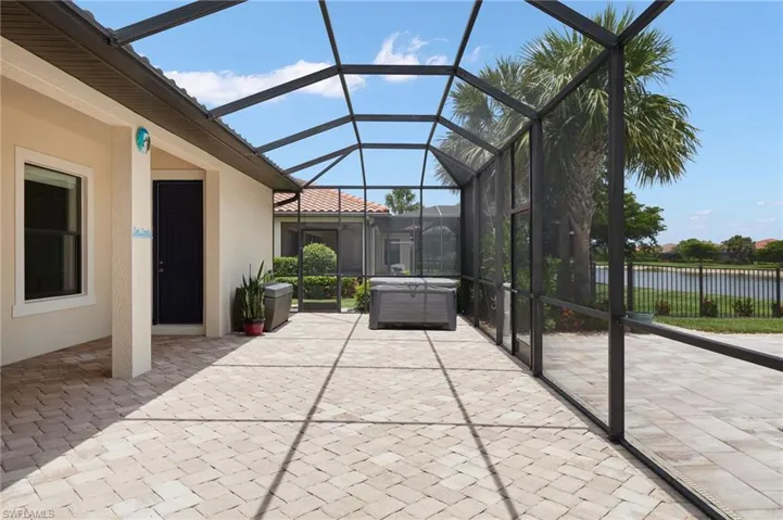 View of patio with a hot tub, glass enclosure, and a water view