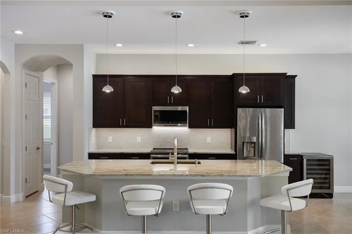 Kitchen featuring stainless steel appliances, wine cooler, arched walkways, a sink, and light tile patterned flooring