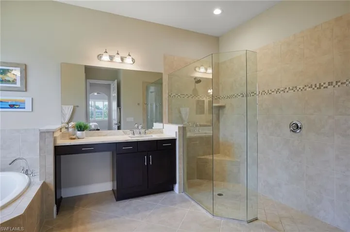 Full bath featuring vanity, a bath, a tile shower, and tile patterned floors