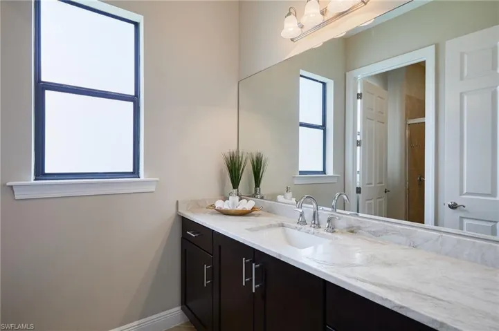 Full bath with vanity, a tile shower, and baseboards