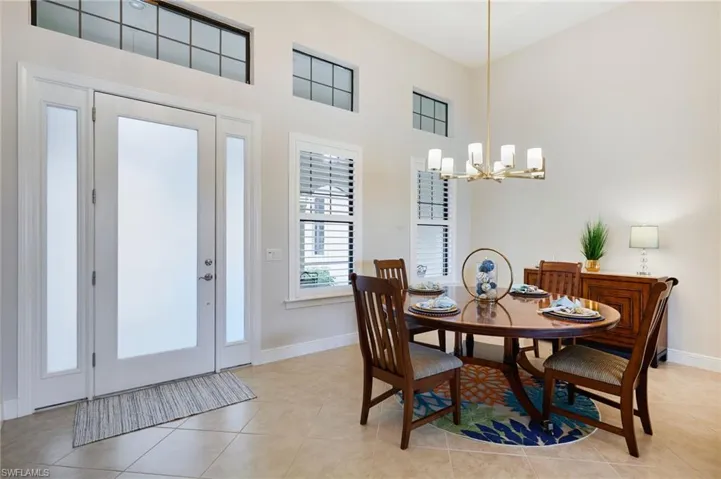 Dining space featuring a chandelier, a towering ceiling, baseboards, and light tile patterned flooring