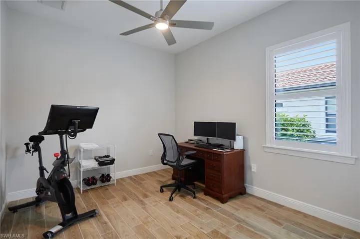 Office with light wood-type flooring, baseboards, and ceiling fan
