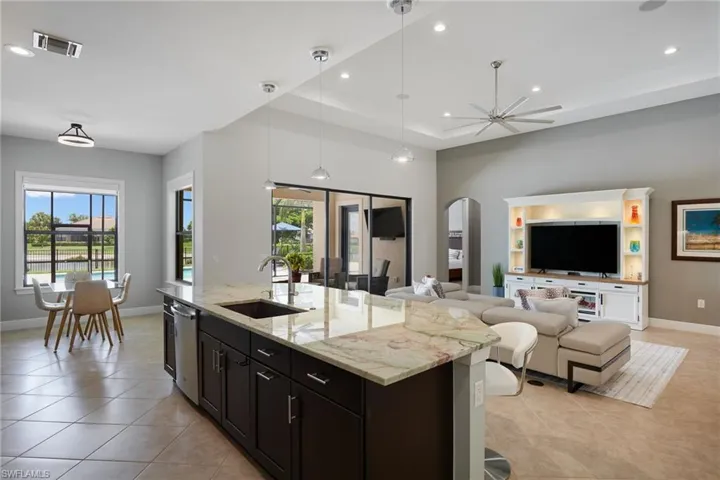 Kitchen featuring arched walkways, a sink, light tile patterned floors, open floor plan, and baseboards