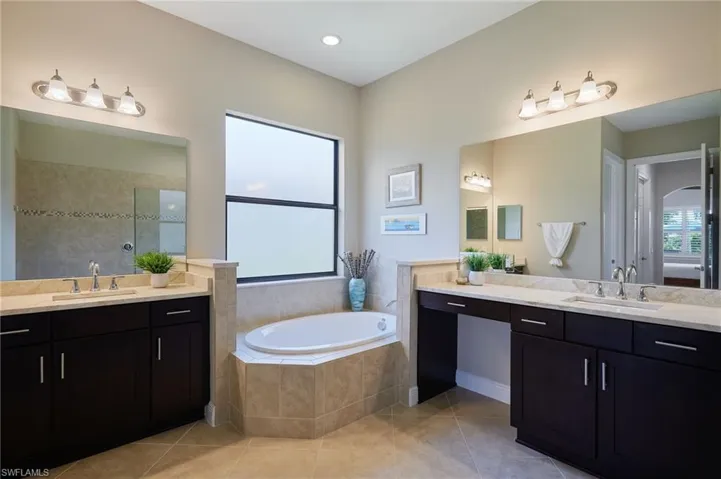 Bathroom with two vanities, a garden tub, tile patterned flooring, and tiled shower