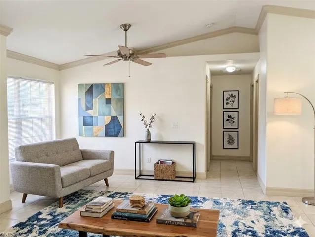Virtual staged Living room with crown molding, vaulted ceiling, a ceiling fan, and light tile patterned floors
