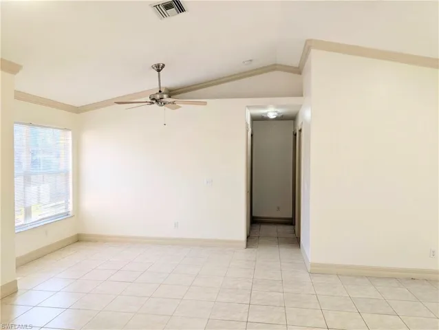Unfurnished room featuring crown molding, ceiling fan, lofted ceiling, and light tile patterned floors
