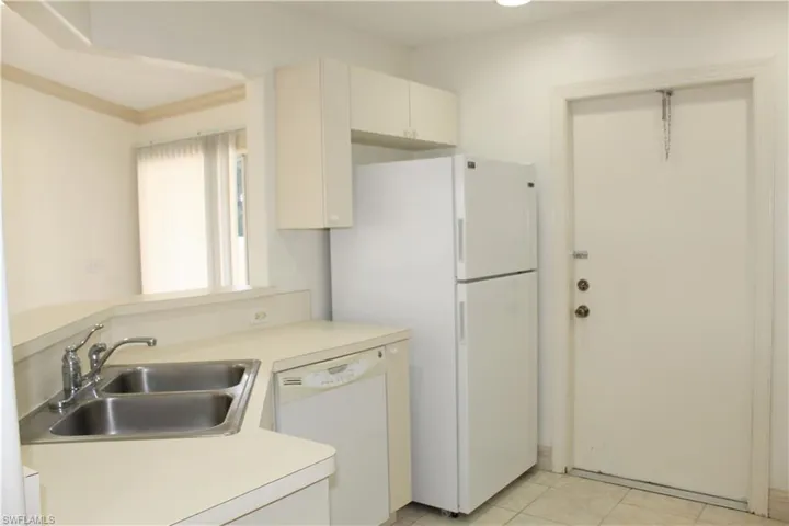 Kitchen featuring white appliances, light countertops, light tile patterned floors, a peninsula, and cream cabinets