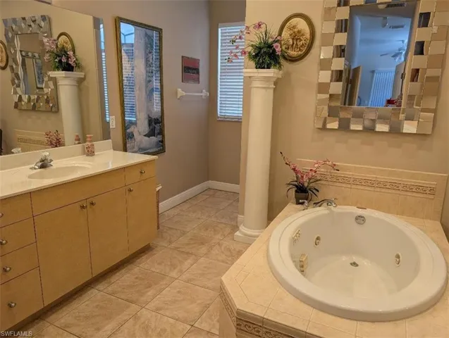 Bathroom featuring a jetted tub, vanity, ornate columns, and tile patterned flooring