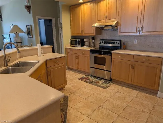 Kitchen with stainless steel appliances, extractor fan, light countertops, and tasteful backsplash