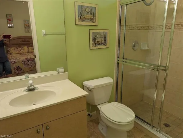 Ensuite bathroom featuring vanity, a stall shower, and tile patterned flooring