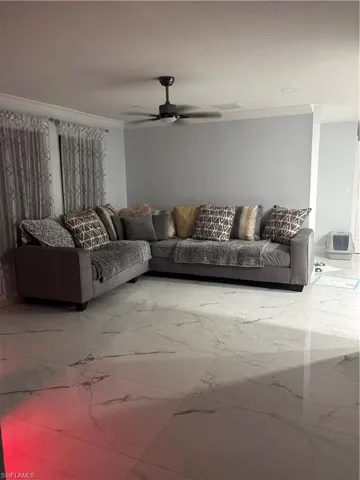 Living area with light marble finish floors, a ceiling fan, and crown molding