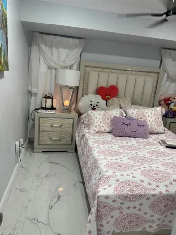 Bedroom featuring light marble finish floors and a ceiling fan