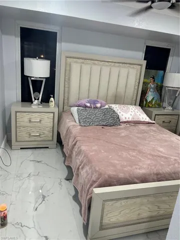 Bedroom featuring marble look tiles and a ceiling fan