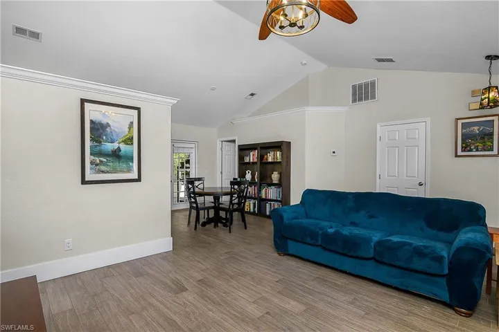Living room featuring visible vents, a ceiling fan, and wood finished floors