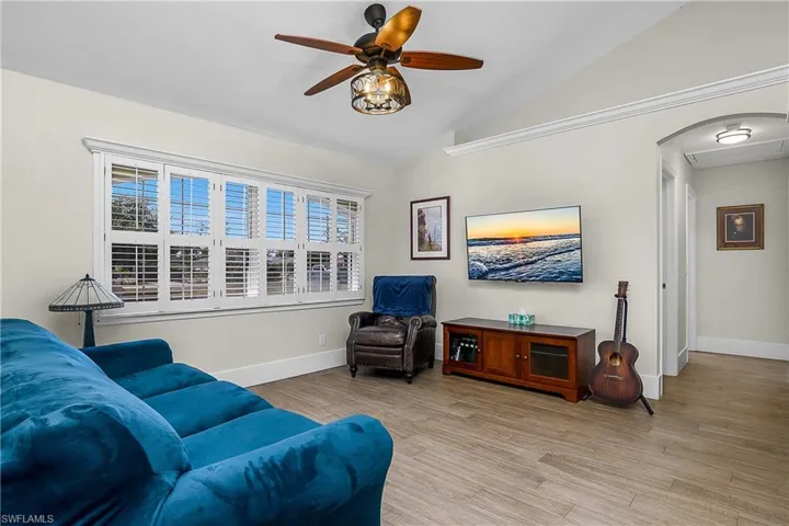 Sitting room with light wood-style floors, baseboards, a ceiling fan, and vaulted ceiling