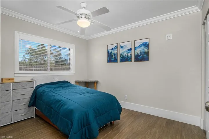Bedroom with dark wood-type flooring, ornamental molding, baseboards, and ceiling fan