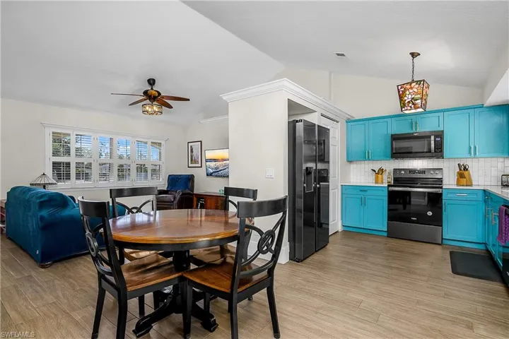 Dining space with visible vents, light wood finished floors, a ceiling fan, and vaulted ceiling