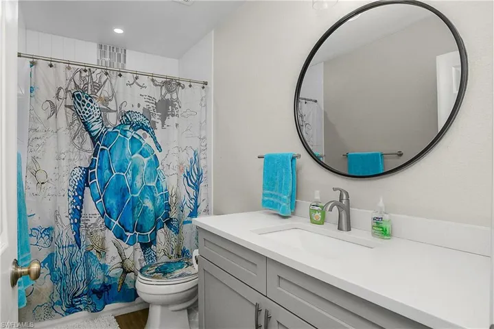 Full bathroom featuring toilet, curtained shower, and vanity