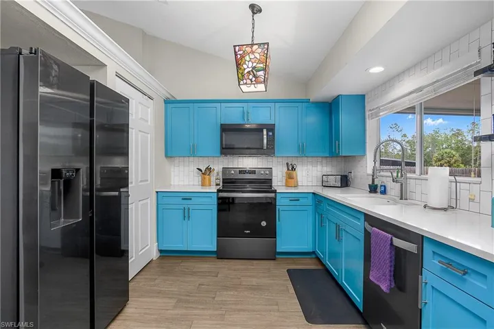 Kitchen featuring stainless steel appliances, tasteful backsplash, a sink, and blue cabinetry