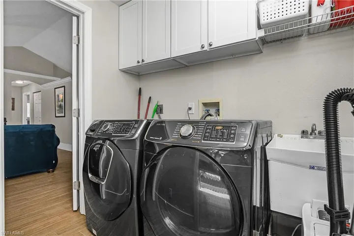 Laundry area with light wood finished floors, washing machine and clothes dryer, a sink, and cabinet space