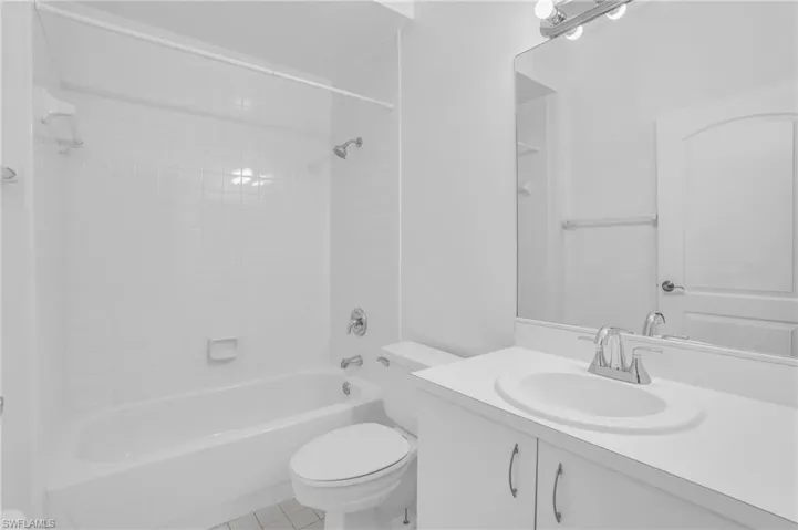 Full bathroom with tiled shower / bath combo, tile patterned floors, toilet, and vanity