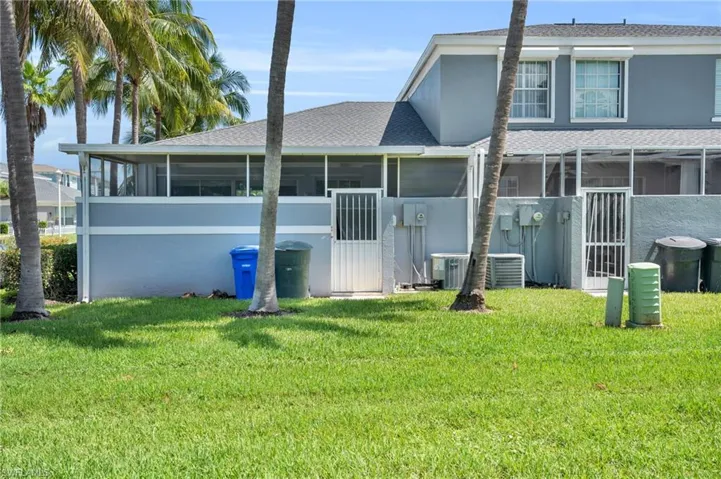 Back of house featuring a sunroom, central air condition unit, and a lawn