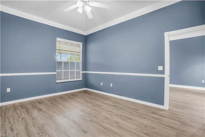 Spare room featuring crown molding, light wood-type flooring, and ceiling fan