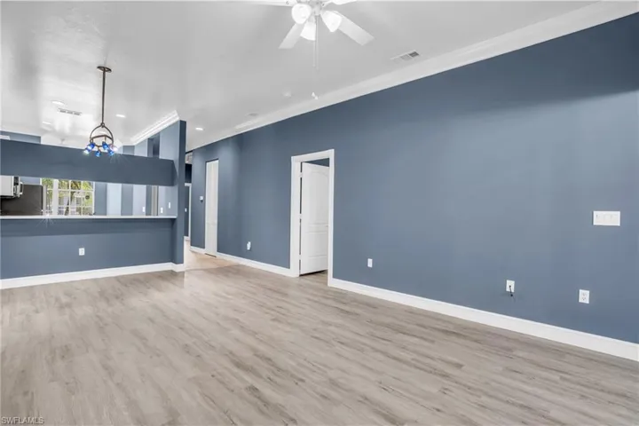 Unfurnished living room featuring ceiling fan with notable chandelier, light hardwood / wood-style flooring, and ornamental molding