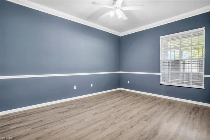 Spare room with wood-type flooring, ceiling fan, and crown molding