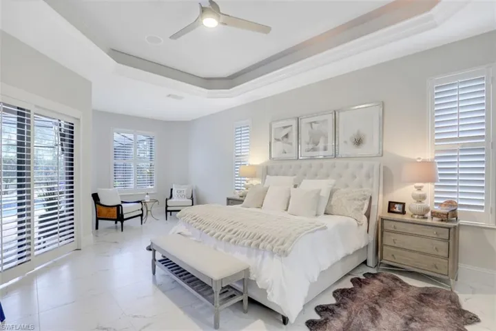 Bedroom with a raised ceiling, access to outside, ceiling fan, tile flooring, and crown molding