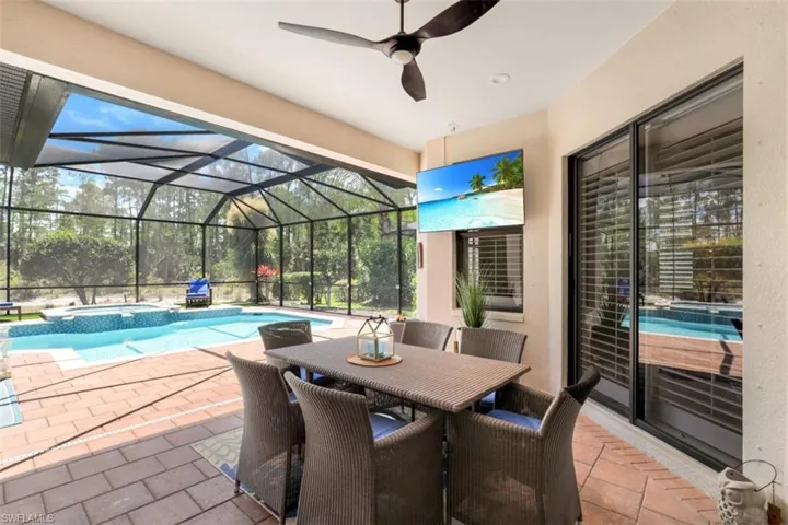 View of patio / terrace with a pool with connected hot tub, screened enclosure and outdoor dining space