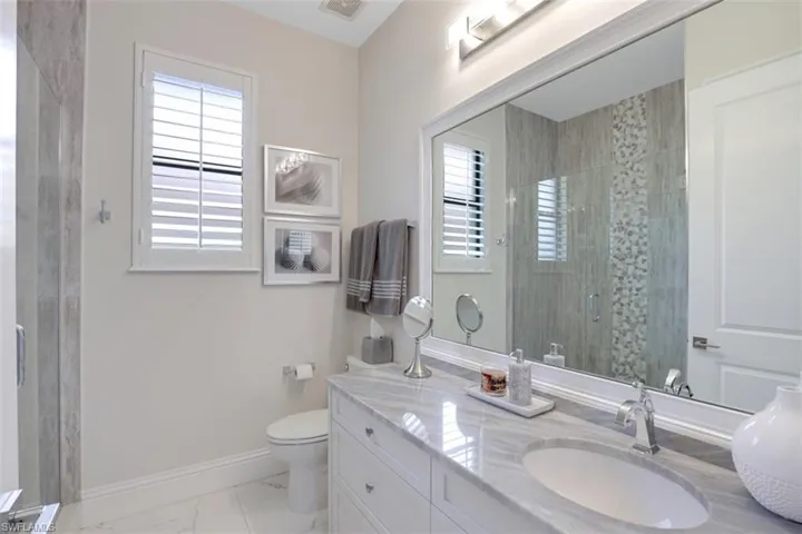 Bathroom featuring a tile shower, vanity, healthy amount of natural light, and light tile floors