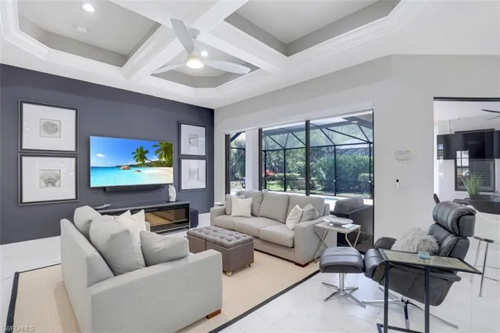 Living area, a ceiling fan, coffered ceiling, marble look tiles, and recessed lighting