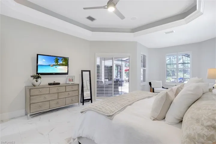 Bedroom with a tray ceiling, a ceiling fan