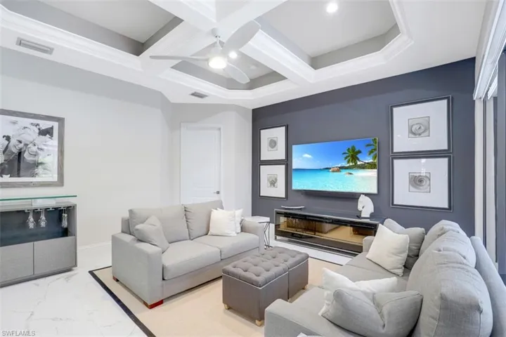 Living area featuring coffered ceiling, a ceiling fan, and tile floors