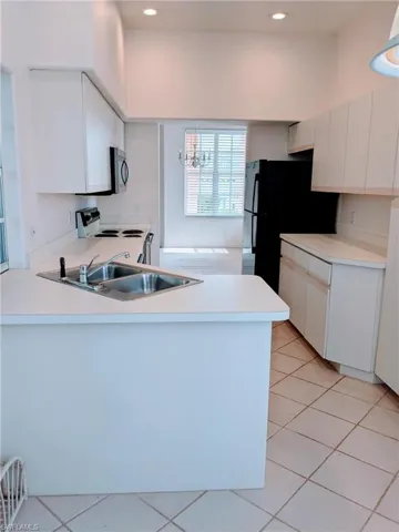 Kitchen featuring electric stove, a peninsula, light countertops, white cabinetry, and recessed lighting