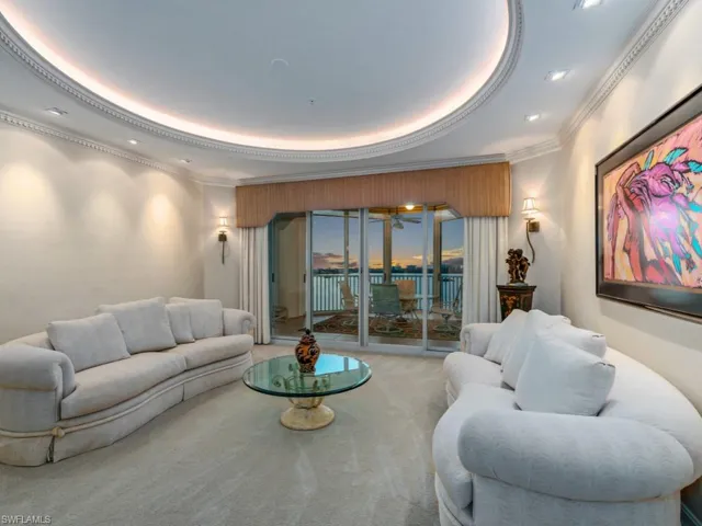Carpeted living room featuring crown molding and a tray ceiling