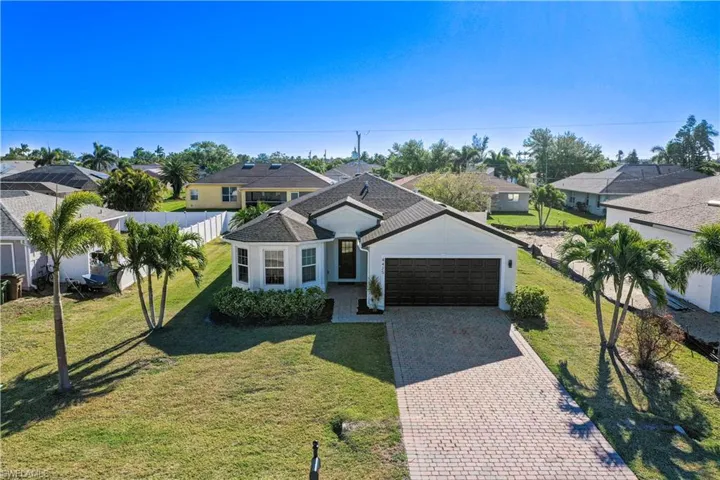 View of front of home featuring fence, an attached garage, stucco siding, a front lawn, and decorative driveway